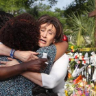 Tres mujeres se abrazan junto a la ofrenda floral frente a la iglesia metodista, en Charleston, este sábado.-Foto:   AP / CURTIS COMPTON
