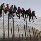 Policías españoles tratan de disuadir a inmigrantes encaramados a la valla de Melilla, fronteriza con Marruecos.-EFE / FRANCISCO G. GUERRERO