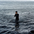 Un refugiado camina entre las aguas tras alcanzar la playa de Lesbos.-AFP / ARIS MESSINIS