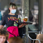 Una camarera lleva una bandeja a una  mesa en una terraza. TOMÁS ALONSO