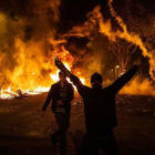 Un manifestante levanta los brazos junto a una hoguera durante la sexta noche de disturbios en Barcelona, este sábado en la plaza de Urquinaona.-DAVID ZORRAKINO