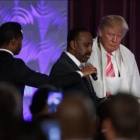 Donald Trump con una túnica de oración durante la visita a una iglesia negra en Detroit.-EVAN VUCCI / AP