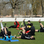 Un grupo de jugadores del Burgos CF realizan estiramientos ante la atenta mirada de Mandiola-I. L. Murillo