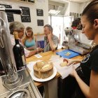 Una camarera prepara un trozo de queso a unos clientes. ECB