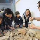 Un grupo de participantes del taller  ‘Con las manos en las piedras’ escuchan atentamente las explicaciones de la monitora sobre cómo se elaboraban las herramientas.-ISRAEL L. MURILLO