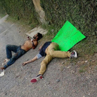 Dos de las víctimas en el suelo, junto a un cartel que les acusa de ladrones, firmado por un grupo de justicieros, este lunes en Guadalajara (México).-EFE