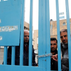 Un grupo de palestinos detrás de la valla de la oficina de la agencia de la ONU para los refugiados palestinos (UNRWA) durante una protesta en la ciudad de Cisjordania.-EFE / ABED AL HASHLAMOUN