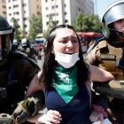 Dos agentes antidisturbios detienen a una joven manifestante en Santiago de Chile.-PABLO VERA (AFP)