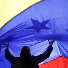 Una mujer sujeta una gran bandera de Venezuela.-ANDREA COMAS (AP)
