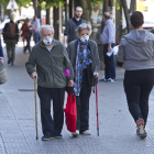 Dos personas mayores  con mascarilla caminan por la acera con la bolsa de la compra. ISRAEL L. MURILLO