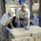 Dos operarios mueven placas de piedra en Villamayor-Ical