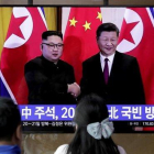 Unos transeúntes observan un programa de TV en el que aparecen el presidente chino Xi Jinping saludando al líder norcoreano Kim Jong-un en Pionyang.-LEE JIN-MAN (AP)