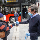 Un conductor de autobús entrega una mascarilla a un usuario del transporte público. SANTI OTERO
