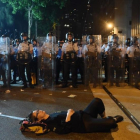 Una manifestante estirada en el suelo bloquea una de las calles de Hong Kong frente a una fila de policías.-AFP / ANTHONY WALLACE