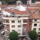 Los bomberos actúan en la cornisa, con parte de los cascotes sobre la acera.-ISRAEL L. MURILLO