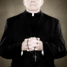 Un sacerdote sujeta un rosario.-EL PERIÓDICO