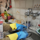 Una persona friega vasos y platos en la cocina de su casa.-ISRAEL L. MURILLO