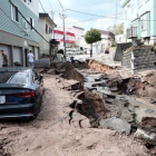 Un vehiculo permanece atrapado entre el lodo en una calle destruida tras el fuerte terremoto.-EFE / JIJI PRESS