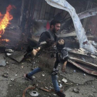 Un hombre sirio portando el cuerpo sin vida de un niño asesinado durante los bombardeos efectuados en la ciudad de Douma,  Siria.-ABD DOUMANY