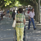 Una mujer pasea a una persona en silla de ruedas.-RAÚL G. OCHOA