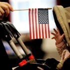 Imagen muestra a un bebe que intenta alcanzar la bandera estadounidense que sostiene su madre en Nueva York.-EPA