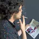 Un joven fuma un cigarrillo mientras lee una revista en Valladolid.-J. M. LOSTAU