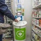 Una mujer deposita el envase de un medicamento en uno de los puntos Sigre ubicados en una farmacia.-ISRAEL L. MURILLO