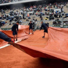 Varios operarios cubren con una lona la pista Philippe Chatrier donde jugaban Djokovic y Thiem.-EFE / JULIEN DE ROSA