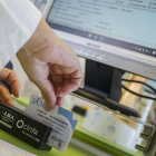 Una dependienta pasa un carnet sanitario por un lector para proporcionarle al usuario el medicamento que se le ha prescrito con receta electrónica, ayer en Burgos.-SANTI OTERO