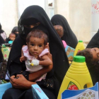 Mujeres yemenís sostienen a sus hijos mientras esperan el reparto de comida en la ciudad de Al Hudayda, en la costa oeste del país.-ABDO HYDER (AFP)