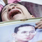 Una mujer llora a las puertas del hospital con la la foto del rey Bhumibol.-EFE / DIEGO AZUBEL