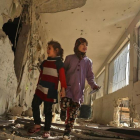 Dos niñas sirias recorren su escuela, destrozada el día anterior por los ataques áereos de la aviación gubernamental, en la sitiada ciudad de Saqba (Guta Oriental), el 9 de noviembre.-/ AFP / AMER ALMOHIBANY