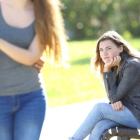 Una chica sentada en el parque siente envidia al ver a una pareja.-123RF