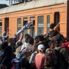 Decenas de inmigrantes y refugiados intentan subir a un tren en una estación de Macedonia con destino a Serbia, el martes.-