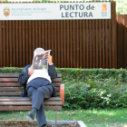 Un hombre lee el periódico junto al punto de lectura del paseo de la Isla.-ISRAEL L. MURILLO