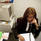 Una mujer atiende una llamada de teléfono en un dispositivo conectado a una línea fija.-ICAL
