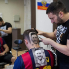Mario Hvala, en plena tarea de esculpir el retrato de Messi en la cabeza de un seguidor del Barça de Novi Sad.-/ AFP