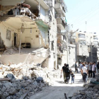 Vecinos de Alepo pasan junto a un edificio destruido en un bombardeo del régimen, este domingo.-Foto:   KHALED KHATEB / AFP / JALED JATEB