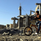 Un niño yemení pasea con su bicicleta junto a los escombros de una vivenda en Saná destrozada por los bombardeos aéreos.-YAHYA ARHAB (EFE)