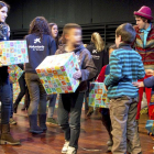 En la imangen voluntarios de CaixaProinfancia entregan regalos a un grupo de niños y niñas.-ECB
