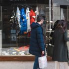 Dos personas miran un escaparate de un comercio en una calle del centro de la capital burgalesa.