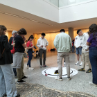 Un grupo de participantes prueban las habilidades de su robot para tirar las latas fuera del círculo.