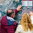 Dos turistas consultan uno de los mapas de la ciudad de Burgos instalado en un Mupi.