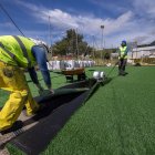 Dos operarios ajustan el nuevo césped artificial del campo de fútbol siete del complejo deportivo José Luis Talamillo.