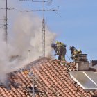 Dos bomberos intervienen desde la cubierta del edificio.