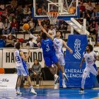 Wembi trata de colar el balón en la canasta ante la oposición de un contrario.