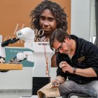 Una exhibición de fabricación de herramientas de piedra, de fondo TIAGo, el robot de PAL Robotics que ya puede responder a un problema fabricando su herramienta para resolverlo.