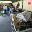 Un usuario y un trabajador con varios objetos para depositar en una zona destinada a electrodomésticos.