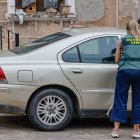 Una agente de la Guardia Civil, junto al vehículo aparcado frente a la casa de la mujer fallecida.