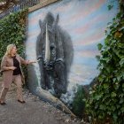Roberto Saiz y Cristina Ayala contemplan uno de los animales prehistóricos recreados en el mural a orillas del Arlanzón.